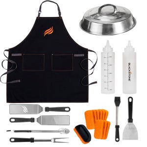 This is a 22-piece Blackstone grilling tool and accessory kit featuring a black apron, a dome cover, two squeeze bottles, a basting brush, a spatula, tongs, and other grilling utensils.