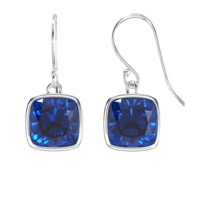 Silver hook earrings with cushion-cut blue gemstones, framed in a silver bezel setting.