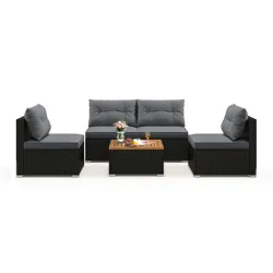 Outdoor patio furniture set with gray cushions, featuring a three-seater sofa, two single chairs, and a coffee table with a wooden top, decorated with flowers, fruit, and drinks.