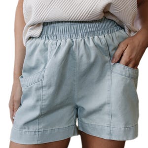 Light blue shorts with an elastic waistband, featuring large front pockets, paired with a textured white top.