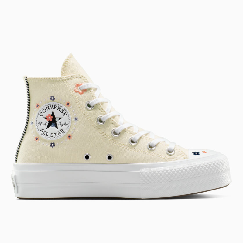 Cream-colored Converse Chuck Taylor Platform shoes with floral embroidery, featuring a classic high-top design, a prominent All Star logo, white laces, and a thick white platform sole.