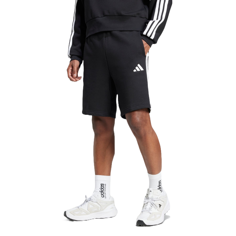 A person is wearing black Adidas shorts with the logo and white stripes on the sides, paired with a matching black sweatshirt and white Adidas socks and sneakers.