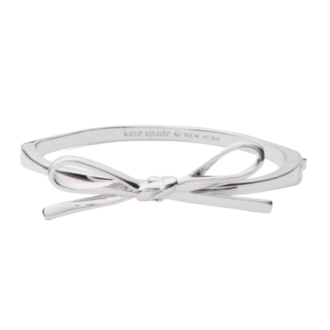 A silver bow bangle with a sleek, minimalist design, labeled \“kate spade NEW YORK\“ on the inside.