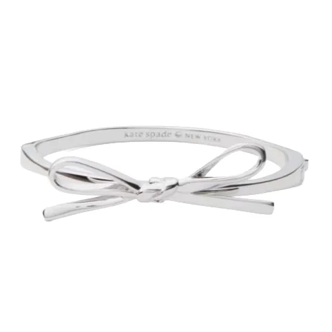 A silver bow bangle with a sleek, minimalist design, labeled \“kate spade NEW YORK\“ on the inside.