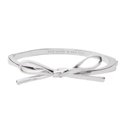 A silver bow bangle with a sleek, minimalist design, labeled \“kate spade NEW YORK\“ on the inside.