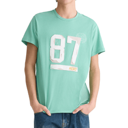 A person wearing a mint green t-shirt with the number \“87\“ and the word \“AERO\“ printed on the front, paired with blue jeans.