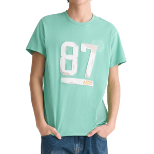 A person wearing a mint green t-shirt with the number \“87\“ and the word \“AERO\“ printed on the front, paired with blue jeans.