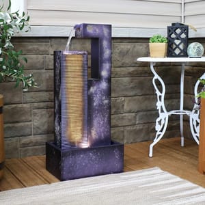 Indoor water feature with galaxy design and cascading water over ribbed texture, next to a small white table with decorative items.