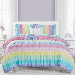 Colorful rainbow-themed bedspread set with ruched texture, featuring matching pillows. Flanked by white nightstands, one with a lamp and clock, set against lavender walls and large windows with sheer curtains.