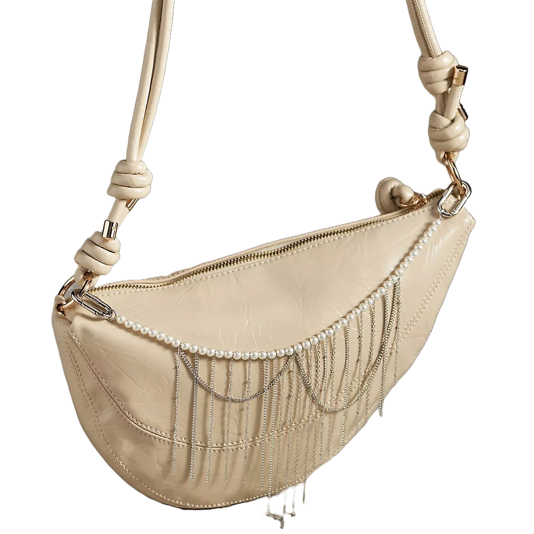 A beige sling bag with a zippered closure features a decorative pearl and silver chain charm that drapes across the front. The bag has a knotted strap and gold-tone hardware.
