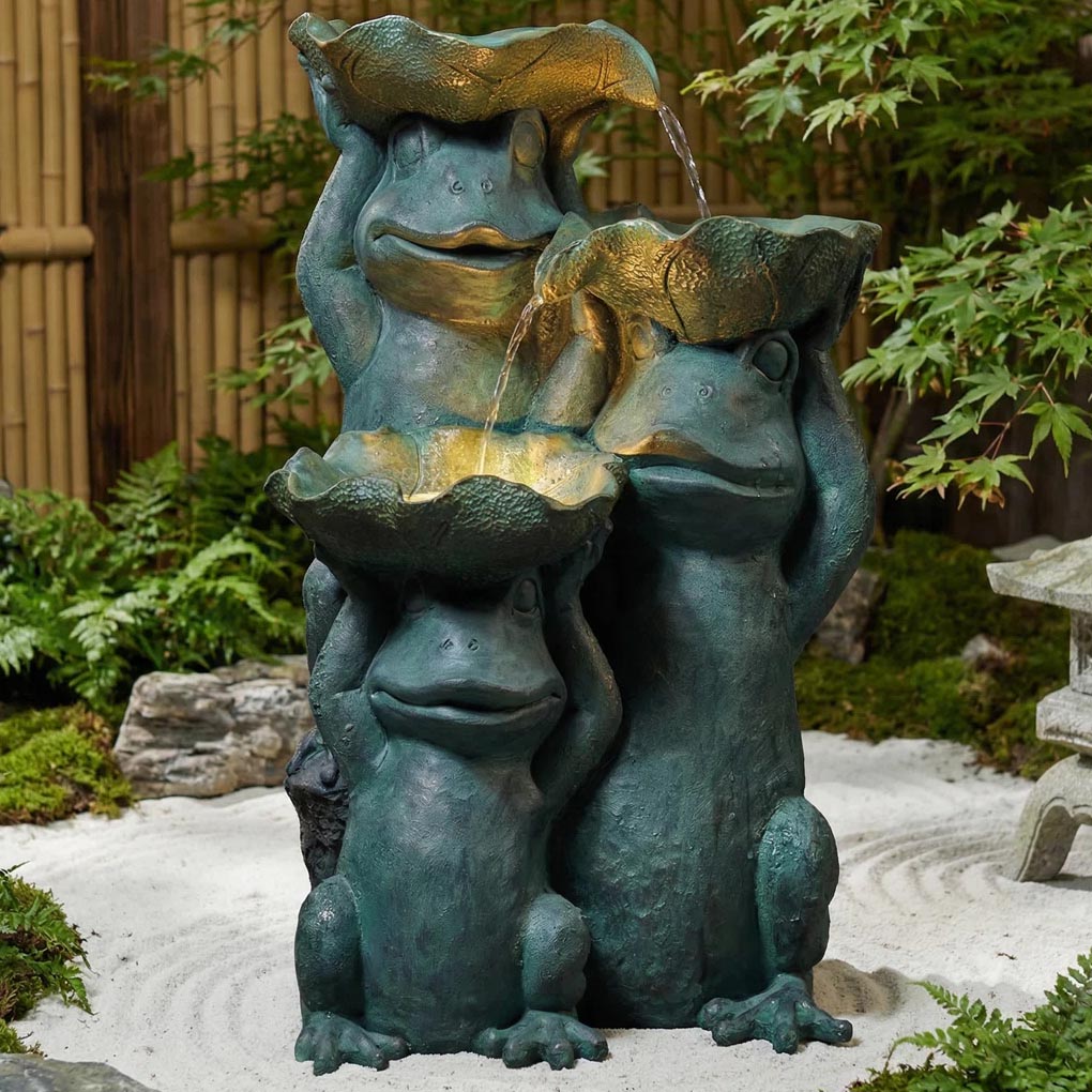 Three whimsical frog sculptures hold large leaves, forming a cascading fountain, set within a serene garden environment.