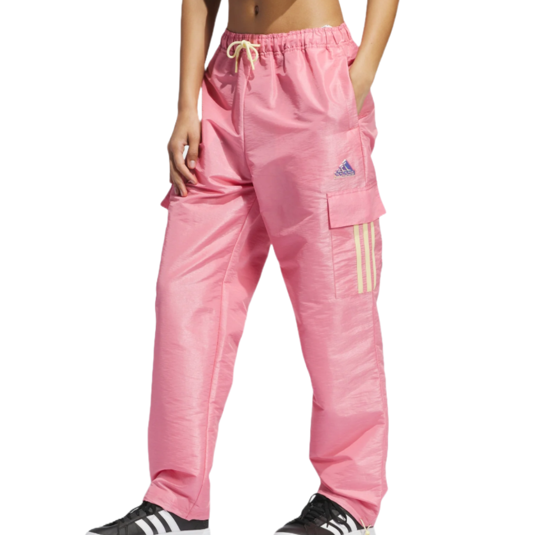 Pink Adidas woven pants with an elastic waistband and drawstring, featuring side pockets and a cargo pocket with three stripes and the Adidas logo. Paired with black and white Adidas sneakers.