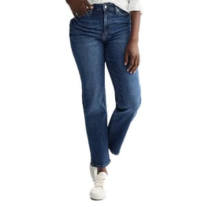 A person wearing blue straight-leg jeans and white sneakers is standing with one leg slightly forward, with a portion of a white shirt visible at the top.