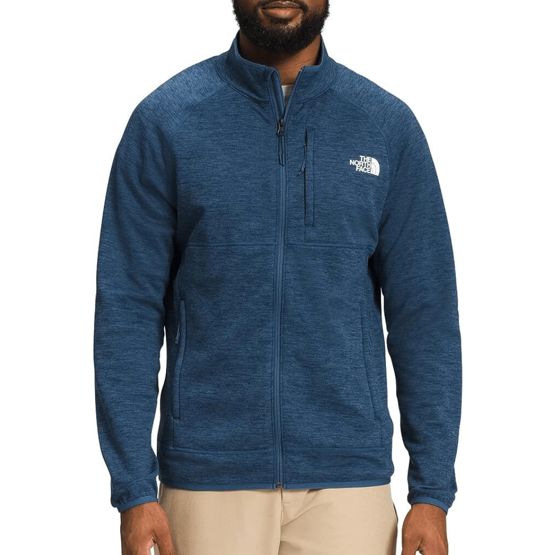 A man wearing a blue full-zip fleece jacket with The North Face logo on the chest, featuring side pockets and a zippered chest pocket.