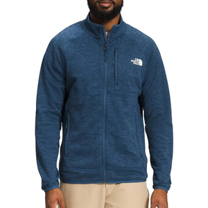 A man wearing a blue full-zip fleece jacket with The North Face logo on the chest, featuring side pockets and a zippered chest pocket.