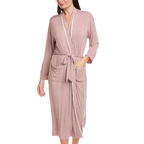 A woman is wearing a mauve, knee-length robe with long sleeves and a waist tie, featuring white trim detailing and pockets.