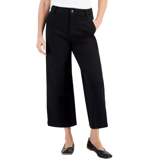 A person is wearing black wide-leg ankle-length trousers with a white top and black flat shoes.