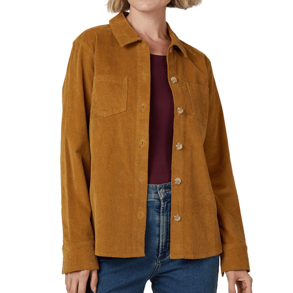 A woman is wearing a mustard-colored corduroy shirt with button closure and chest pockets, paired with blue jeans and a maroon top underneath.
