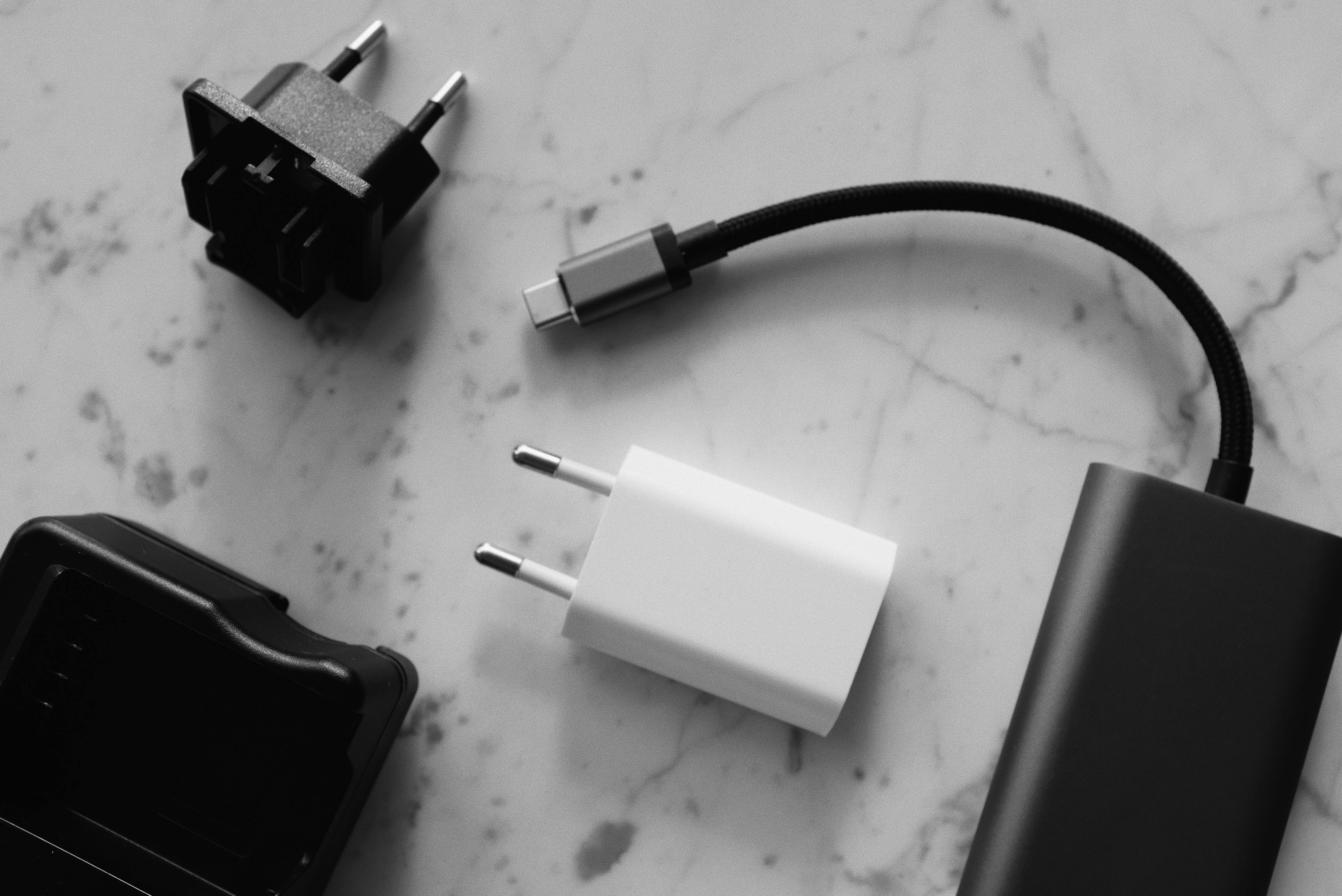 Various power adapters and a USB-C cable are displayed on a marbled surface.