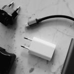 Various power adapters and a USB-C cable are displayed on a marbled surface.