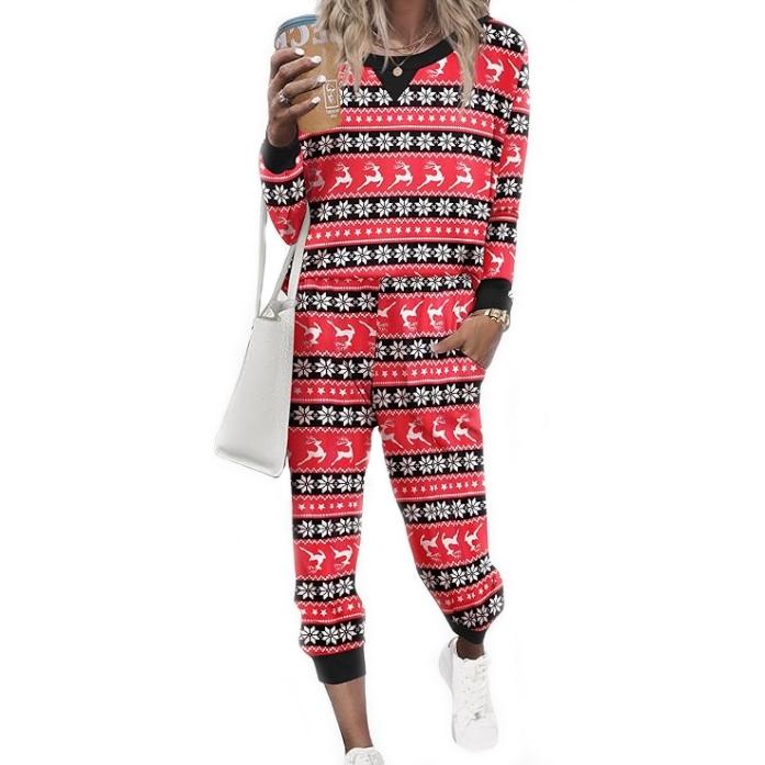 A women's loungewear set featuring a red and black festive pattern with reindeer and snowflake designs. The set includes a long-sleeve top and matching pants, accessorized with white sneakers and a white bag.