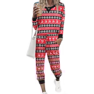 A women's loungewear set featuring a red and black festive pattern with reindeer and snowflake designs. The set includes a long-sleeve top and matching pants, accessorized with white sneakers and a white bag.