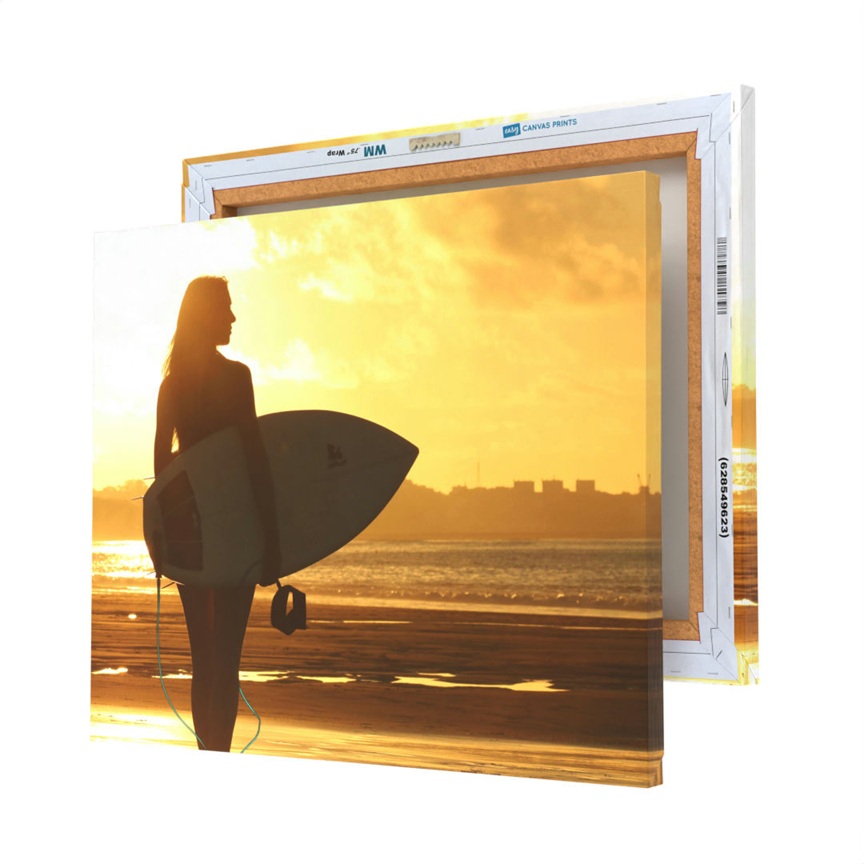 Canvas print featuring a silhouette of a surfer holding a board at sunset, with a visible wooden frame and canvas edge.