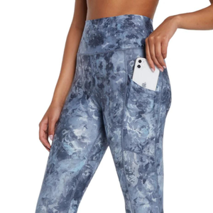 Blue camouflaged patterned leggings with a pocket containing a white smartphone.
