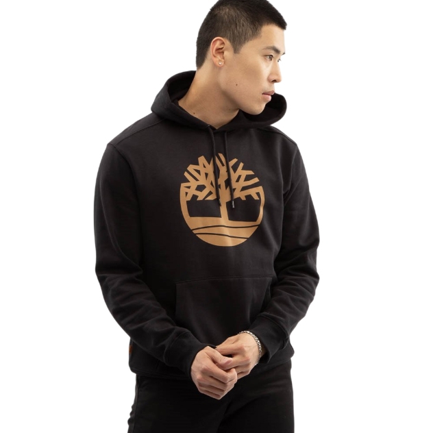 A person is wearing a black hoodie featuring a gold tree logo on the front. The hoodie has a drawstring and a front pocket.