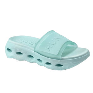 A light blue foam slide sandal with a thick sole featuring circular cutout patterns and a wide strap embossed with text.