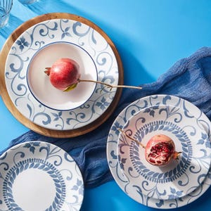 12pc Corelle Dinnerware set featuring plates with elegant blue floral and vine patterns on a white background, accompanied by wooden chargers and a decorative blue cloth. Includes a mix of dinner and side plates.