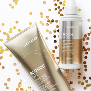 Two Joico Blonde Life hair care products: a brightening conditioner and a brightening veil spray, amidst gold confetti.