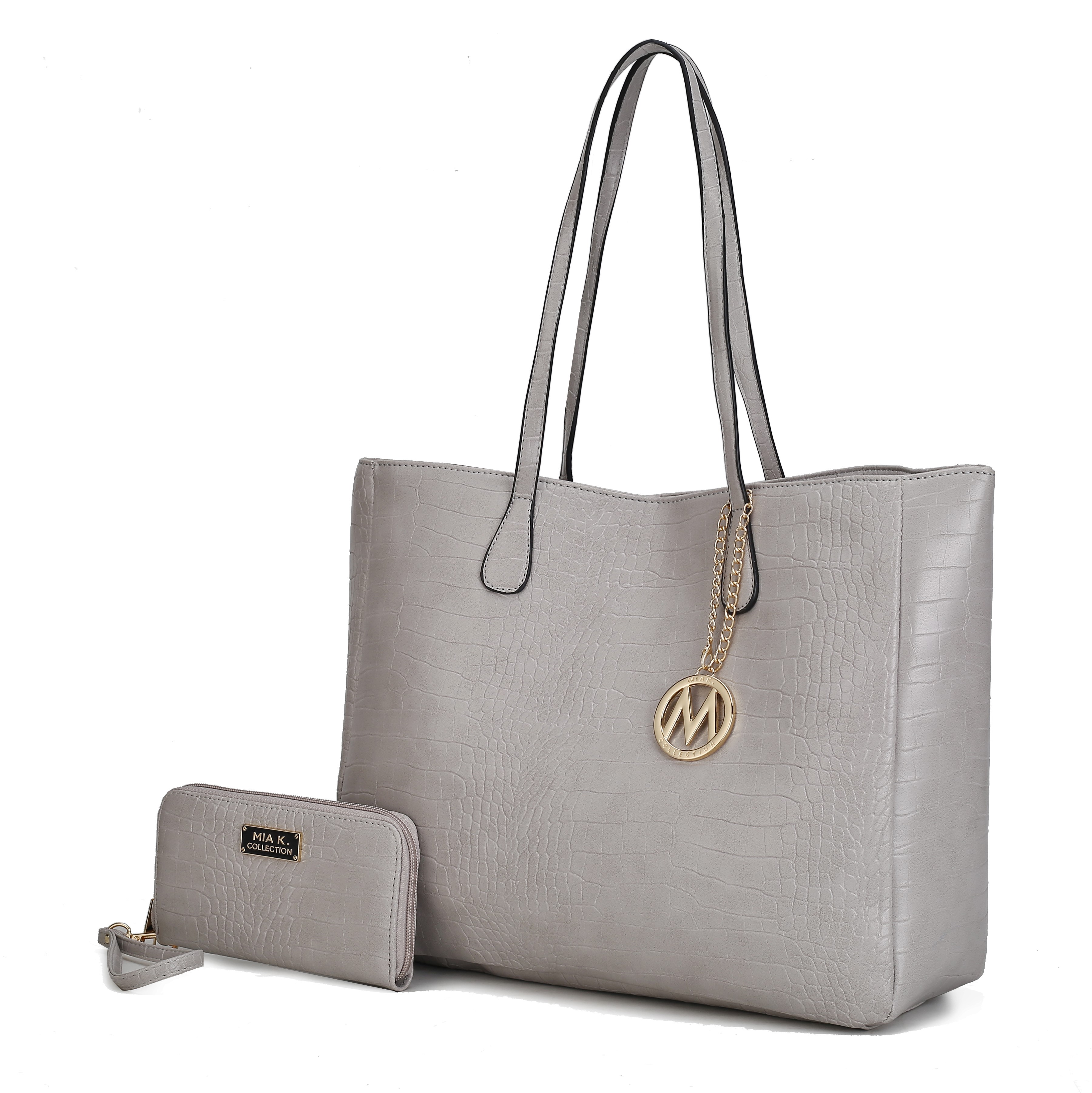 A light gray faux leather tote bag with a crocodile pattern features two handles and a decorative gold-colored charm. It is paired with a matching wallet that has a wristlet strap.