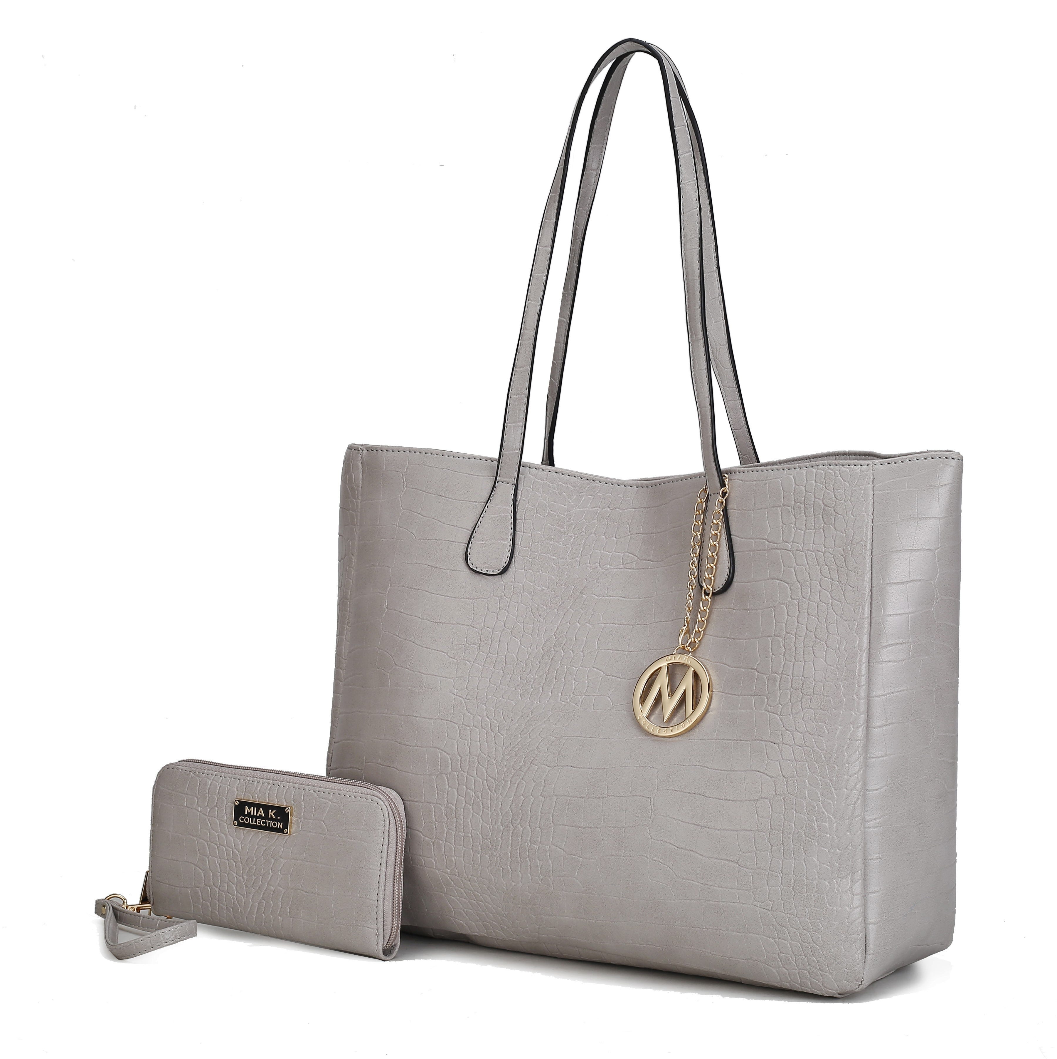 A light gray faux leather tote bag with a crocodile pattern features two handles and a decorative gold-colored charm. It is paired with a matching wallet that has a wristlet strap.