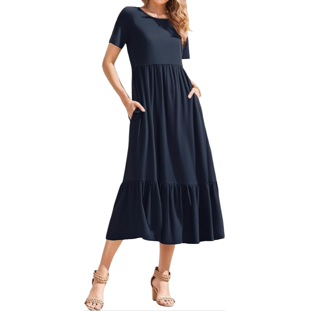 A navy blue short-sleeve midi dress features a loose fit with an empire waist and tiered skirt. It includes pockets on each side and is paired with braided heeled sandals.