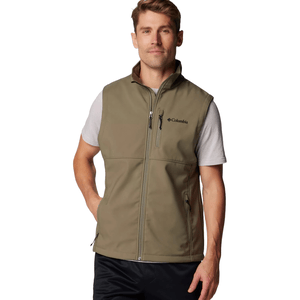 A man wears a Columbia olive-green zip-up vest with a chest and side pocket, layered over a short-sleeve t-shirt.