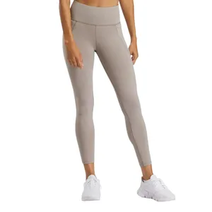 A person is wearing high-waisted, taupe-colored leggings paired with a white crop top and white sneakers.