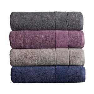 Stack of four rolled Vera Wang Turkish bath towels in gray, purple, beige, and navy, showcasing plush, absorbent fabric.