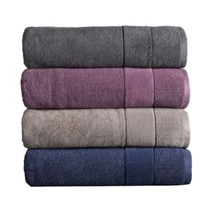 Stack of four rolled Vera Wang Turkish bath towels in gray, purple, beige, and navy, showcasing plush, absorbent fabric.