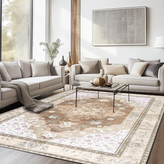 A contemporary living room with a beige and gray color scheme, featuring two sofas, a modern coffee table, decorative vases, and a patterned area rug.