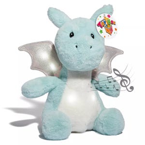 A plush light blue dragon with metallic silver wings and a white belly, featuring a tag that reads \“Toy Box.\“ Musical notes are illustrated near the dragon, suggesting it may play music.