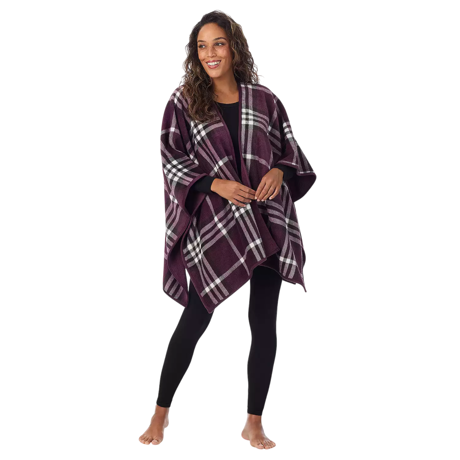 A woman is wearing a purple plaid poncho with draped sleeves over black leggings. She is standing barefoot and smiling.