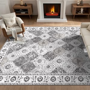 A living room features a patterned area rug with a floral and geometric design, placed between two armchairs and a sofa, in front of a lit fireplace.