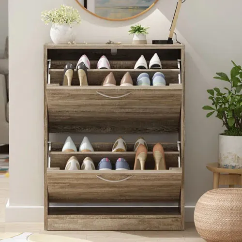 Wooden shoe storage cabinet with three tilt-out drawers, each holding four pairs of shoes. The compact design includes a light brown finish, curved handles, and decorative items on top.