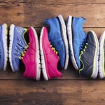 Three pairs of colorful running shoes arranged side by side on a wooden floor.