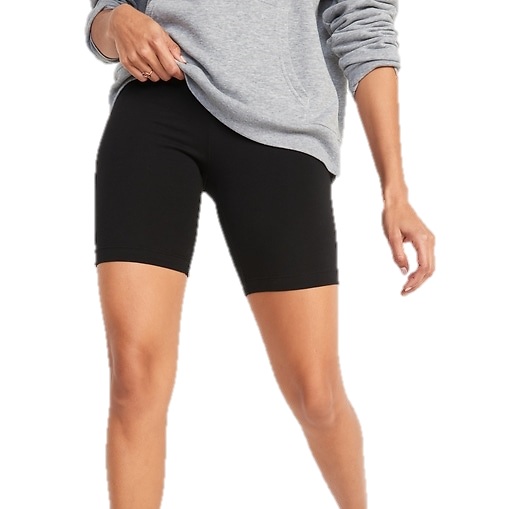 A person is wearing black bike shorts paired with a gray sweatshirt. Their right hand is partly in the sweatshirt's pocket, and they're standing casually.