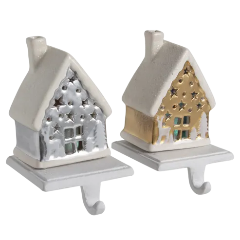 Two small, decorative house-shaped stocking holders with hooks, featuring a snowy design in silver and gold colors.