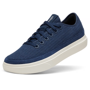 Allbirds Men's Wool Shoes feature a dark blue knit exterior with matching laces and a white, cushioned sole, offering a casual and comfortable style.