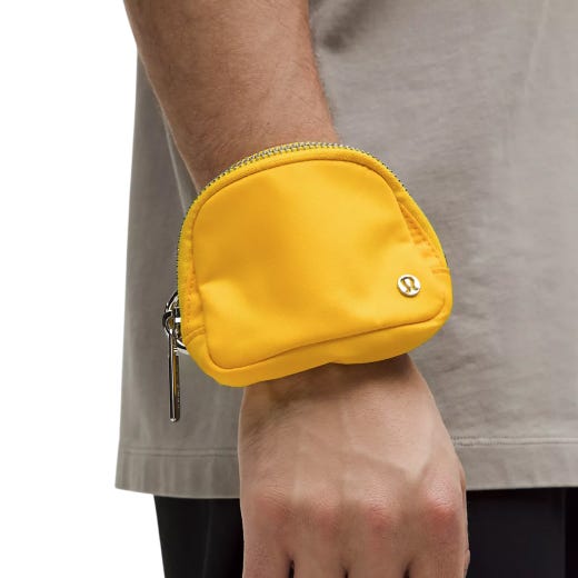 A small, yellow zippered pouch, emblazoned with a logo, designed to be worn on the wrist, suitable for carrying small personal items.