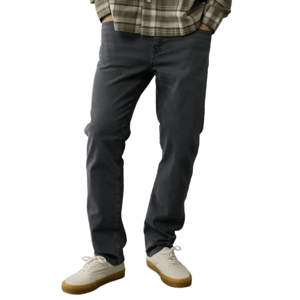 A person is wearing dark gray jeans paired with white sneakers featuring gum soles and an olive plaid long-sleeve shirt.